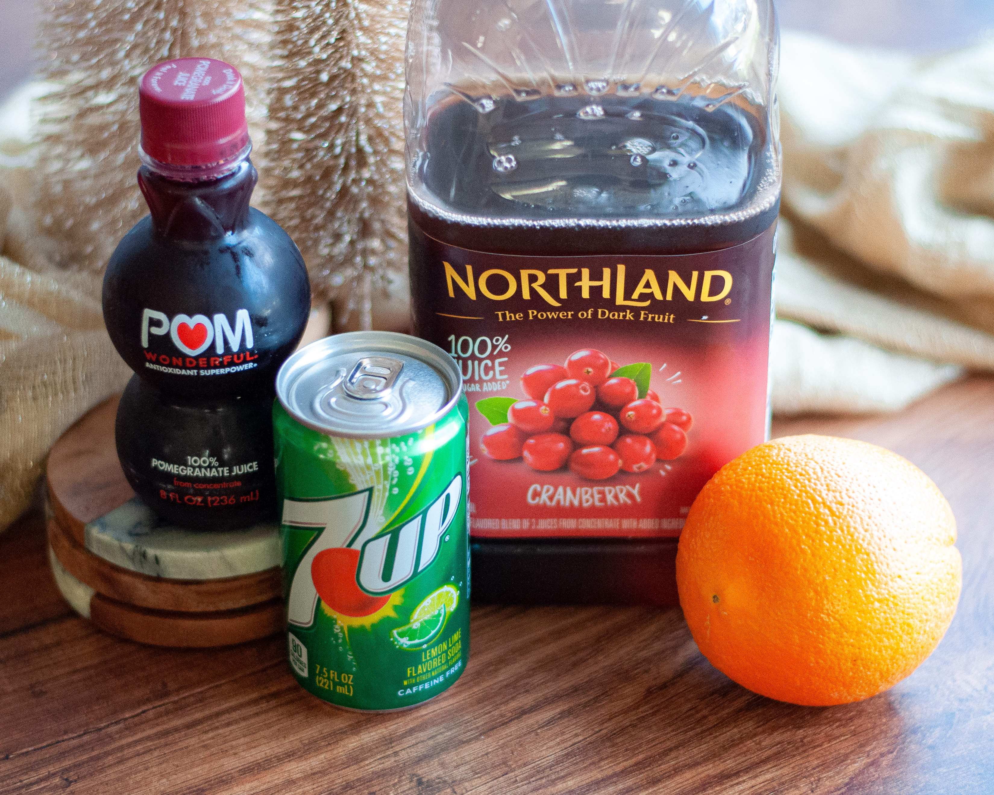 Ingredients needed for this easy mocktail recipe. This includes 100% cranberry and pomegranate juices, an orange, and lemon-lime soda.