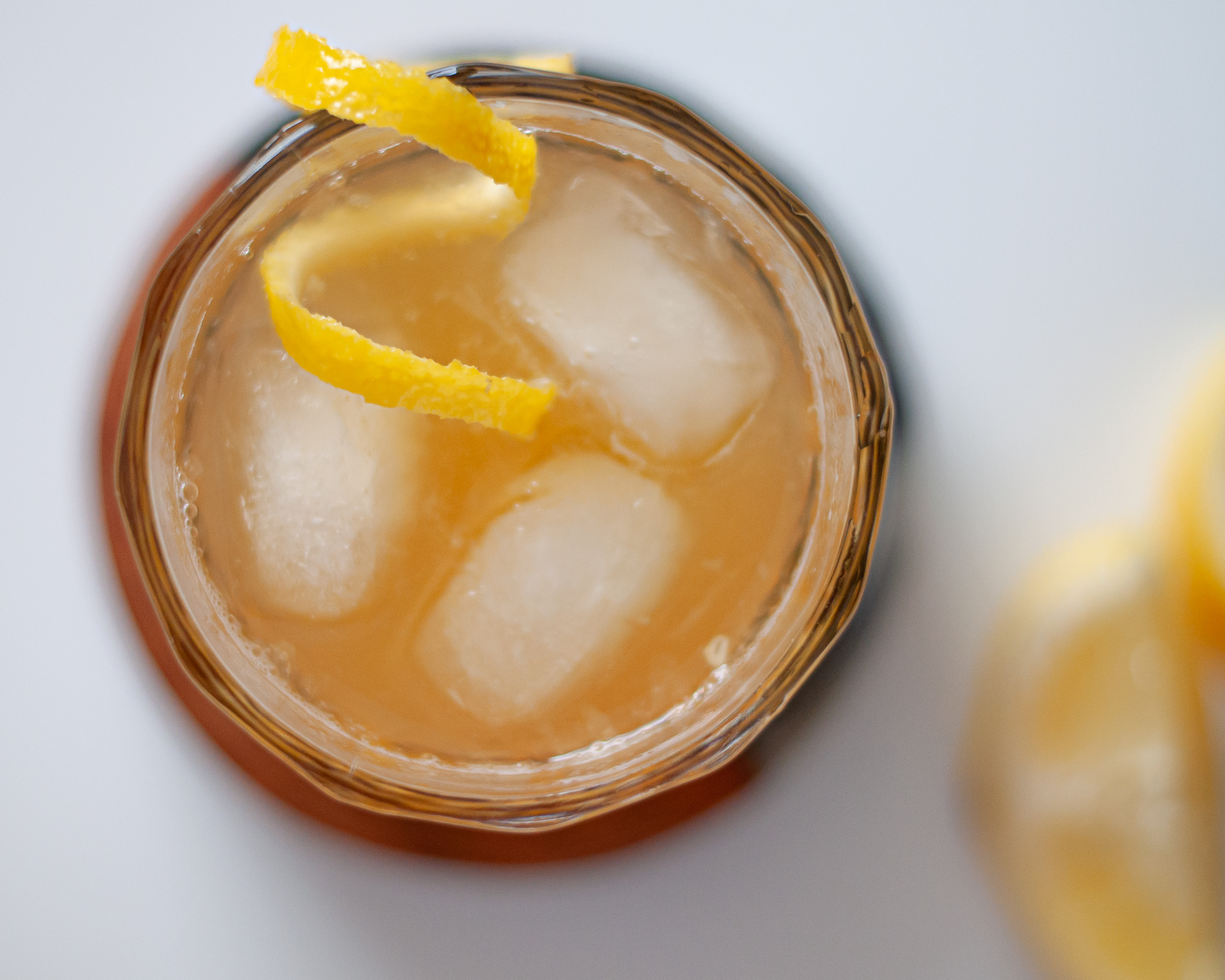 Top down view of a homemade Gold Rush Cocktail served on ice with a lemon twist