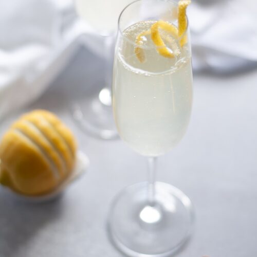 close up for a champagne flute filled with a classic french 75 cocktail with a lemon twist.