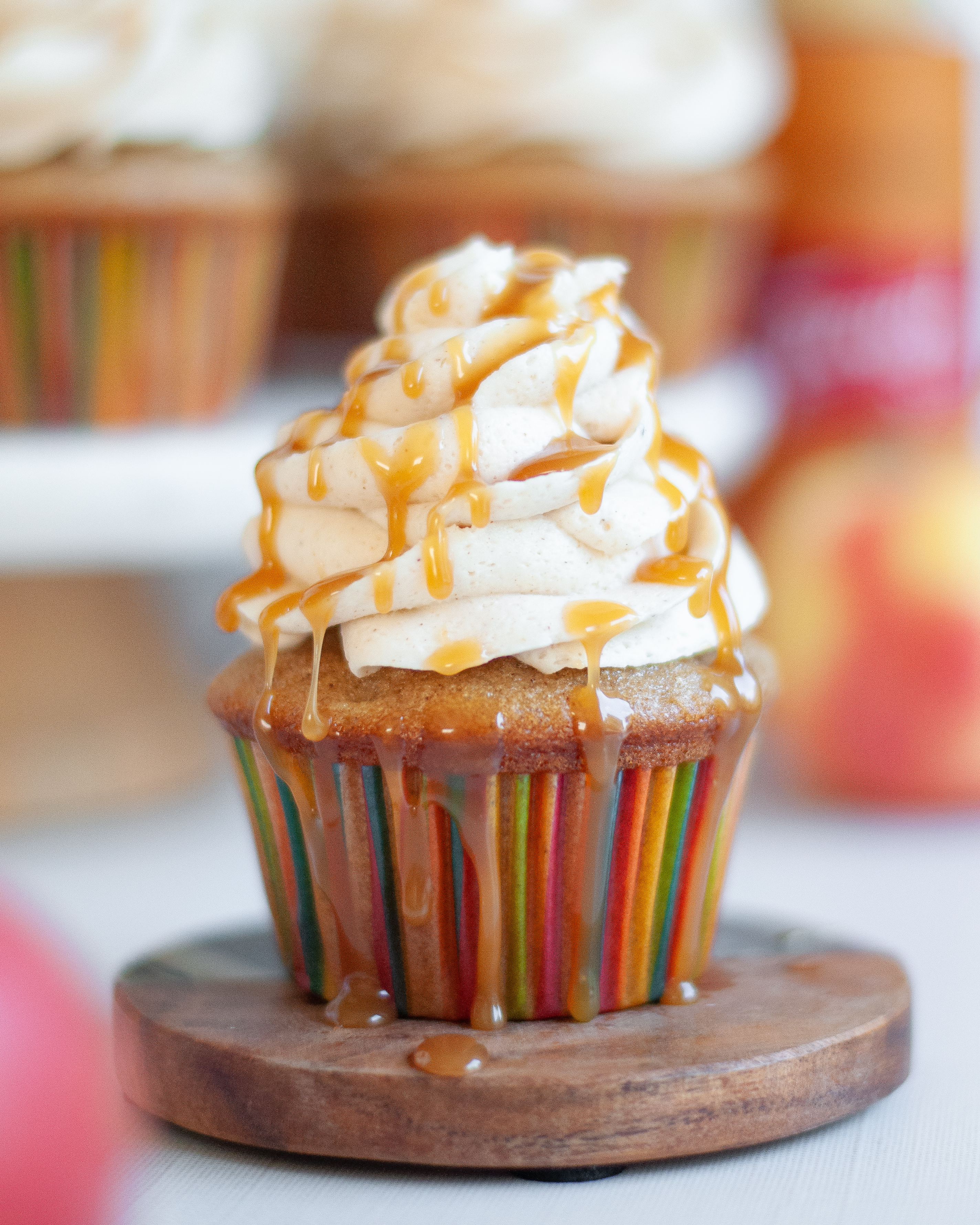 Close up of an apple spice cupcake topped with spiced buttercream frosting with dripping caramel drizzle.