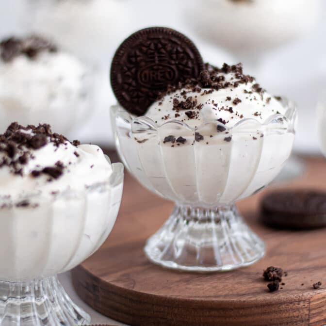 Series of glass serving dishes filled with this no bake Oreo dessert recipe. The center dish is in focus and is garnished with a full Oreo.