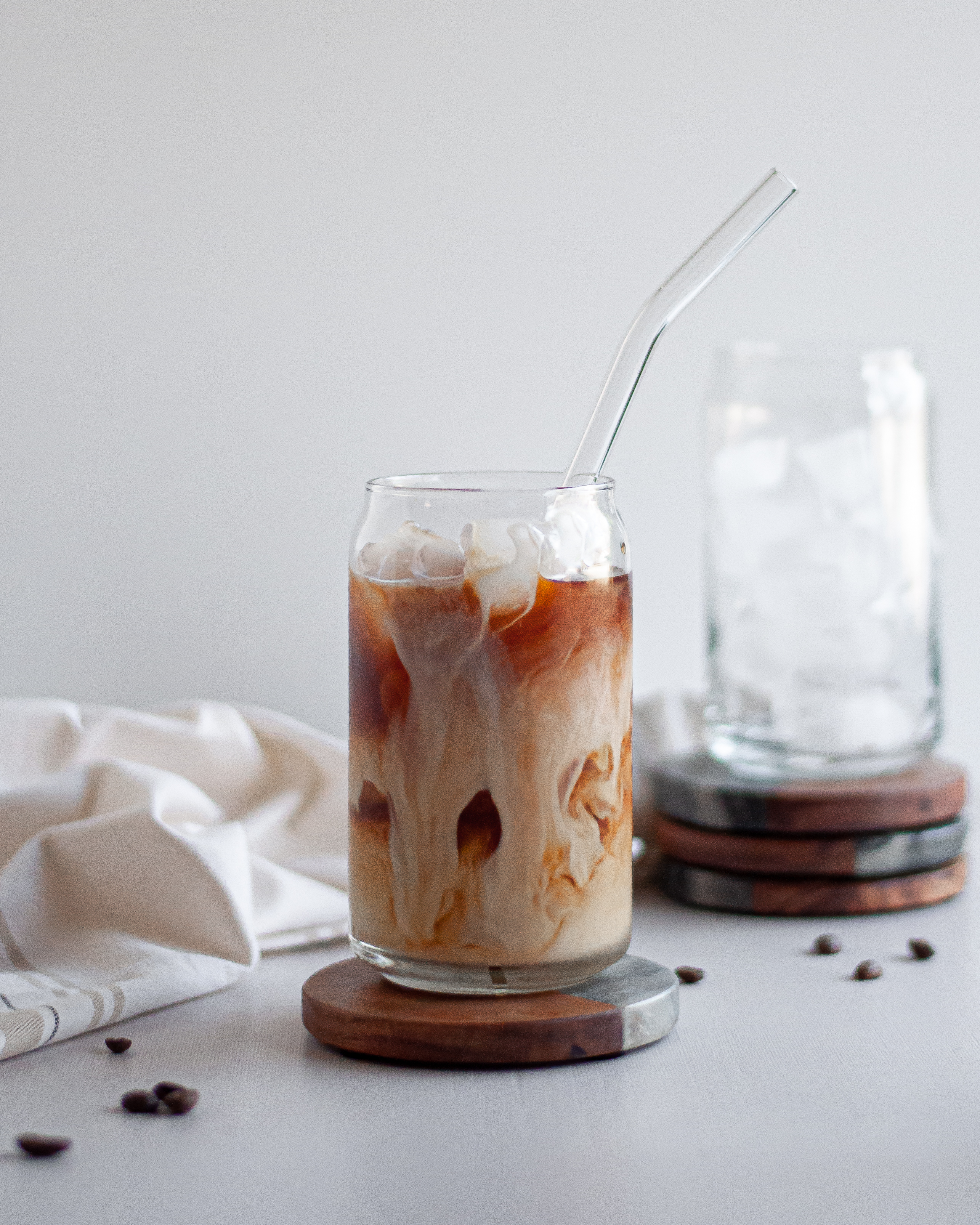 Homemade cold brew coffee served in a glass with a straw, with swirls of milk throughout