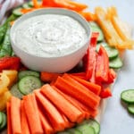 a serving bowl filled with greek yogurt ranch dip and surrounded by a variety of fresh veggies cut up and ready to be dipped!