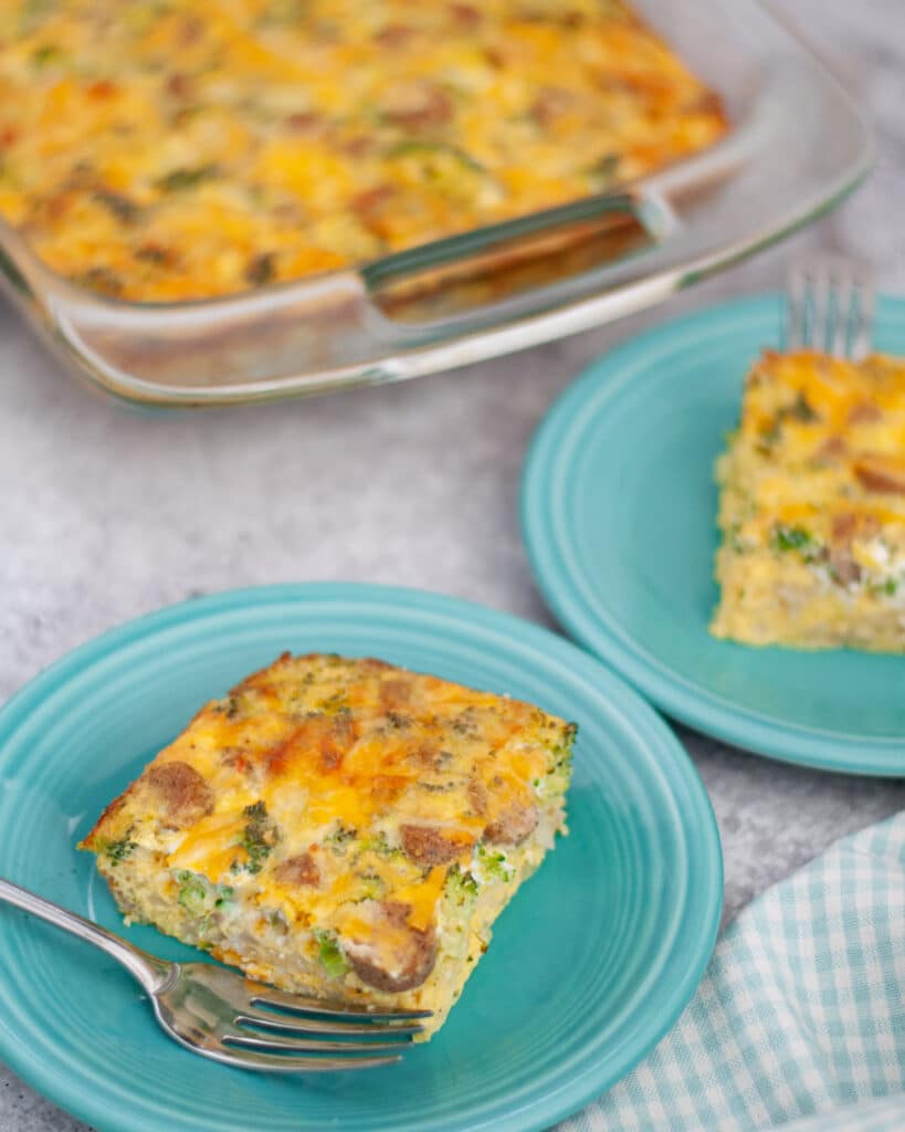 Another view of this easy breakfast casserole recipe, showing the pan next to two plates with slices of egg bake ready to eat