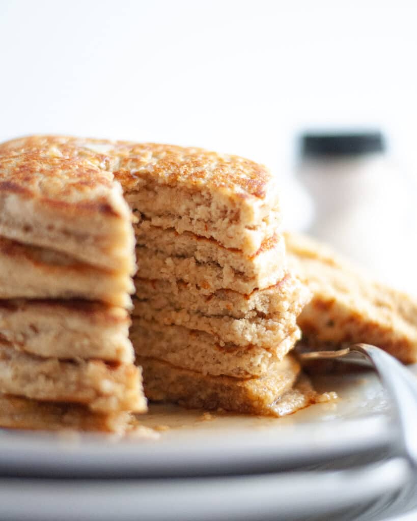 Close up shot of a stack of healthy protein pancakes with a slice out of them, showing off the fluffy texture.