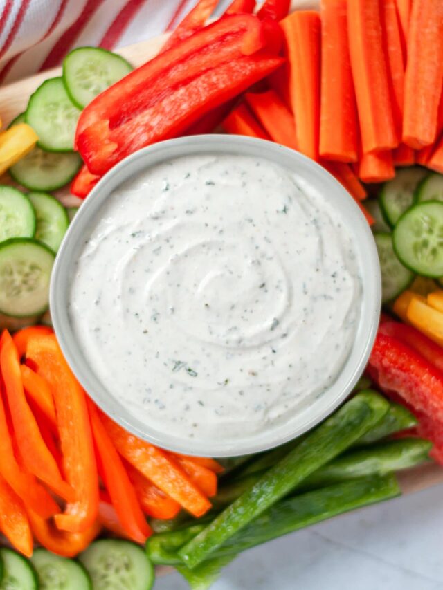 a serving bowl filled with greek yogurt ranch dip and surrounded by a variety of fresh veggies cut up and ready to be dipped!