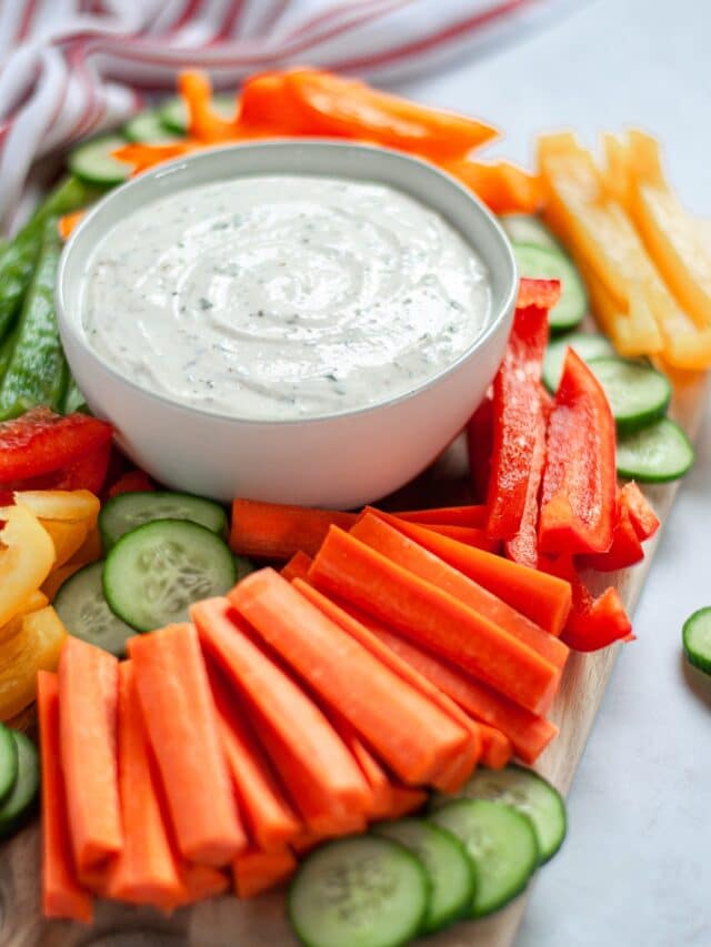 Close-up shot of a platter of sliced carrots, peppers, and cucumbers surrounding a bowl of 3-ingredient ranch dip.