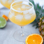 two glasses filled with this Skinny Pineapple Margarita mixture and rimmed with sugar.