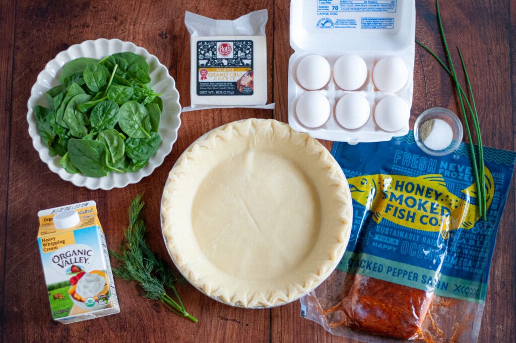 ingredient needed to make this smoked salmon spinach quiche recipe. this includes a frozen pie crust, heaving whipping cream, fresh spinach, fresh dill, fresh chives, gruyere cheese, eggs, salt, pepper, and smoked salmon.