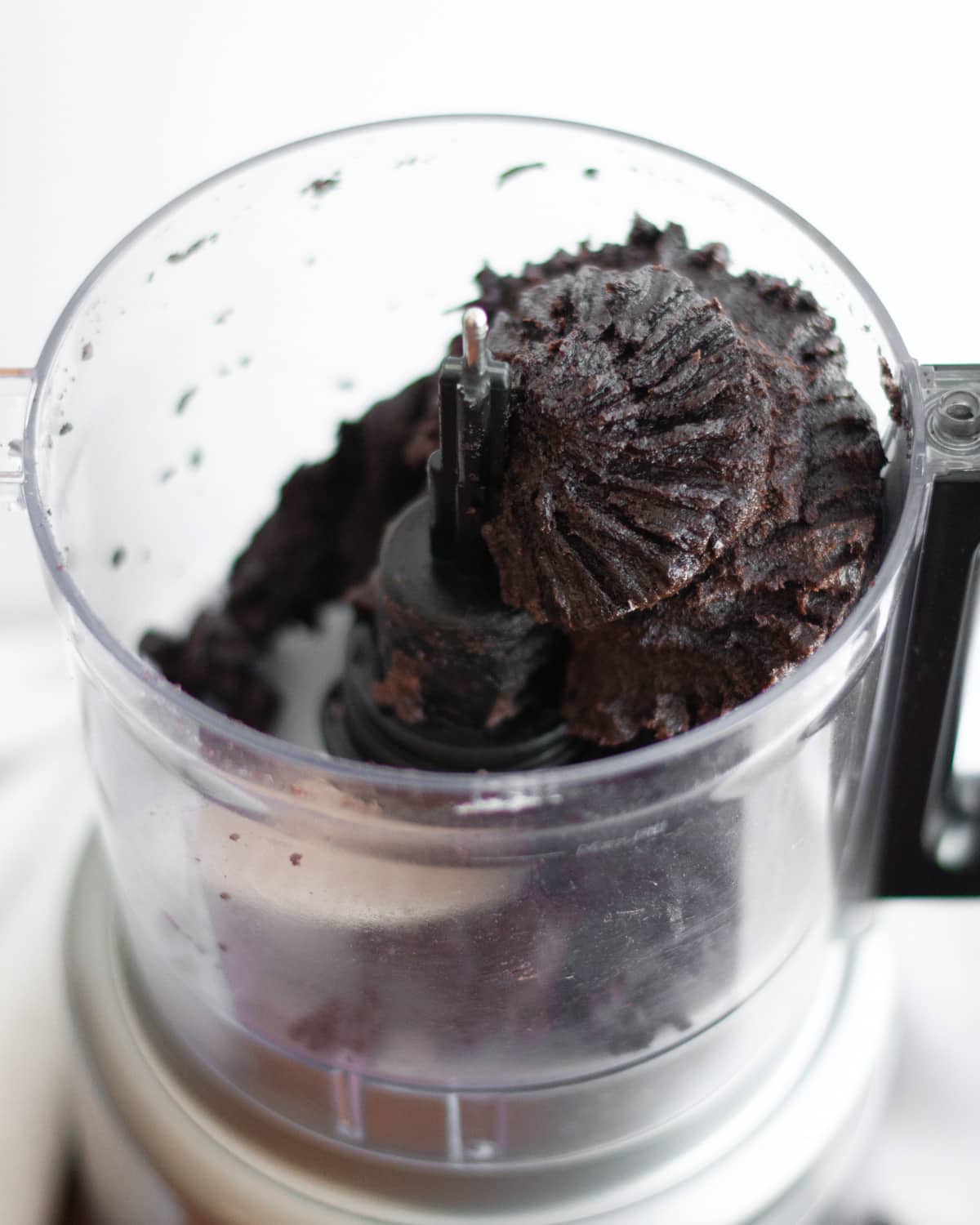 process shot showing how to make oreo balls. showing the oreo and cream cheese filling being mixed up in a food processor.