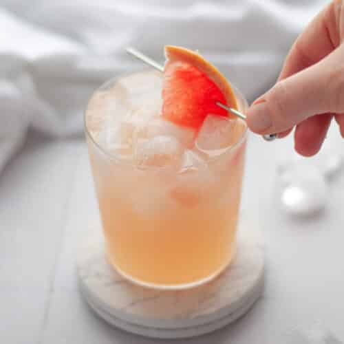 process shot showing the garnish being placed on a finished pink grapefruit mocktail drink.