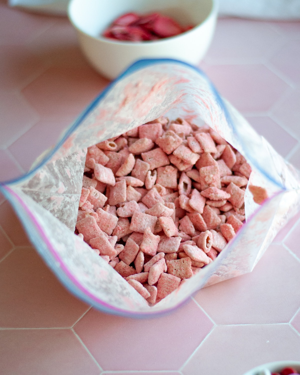 process shot: a zip top bag of freshly shaken valentines muddy buddies open to show the well coated cereal.