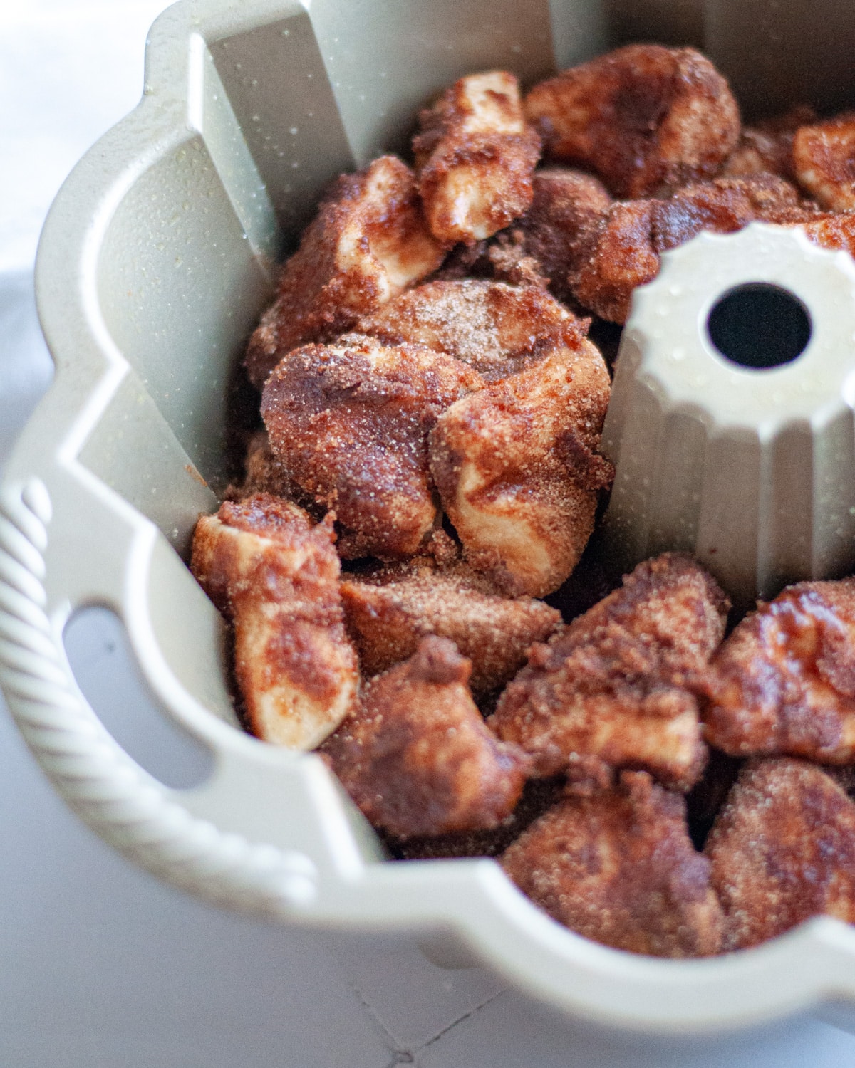 all biscuit pieces dipped in butter, cinnamon, and sugar layered in a bundt pan and ready to go in the oven.