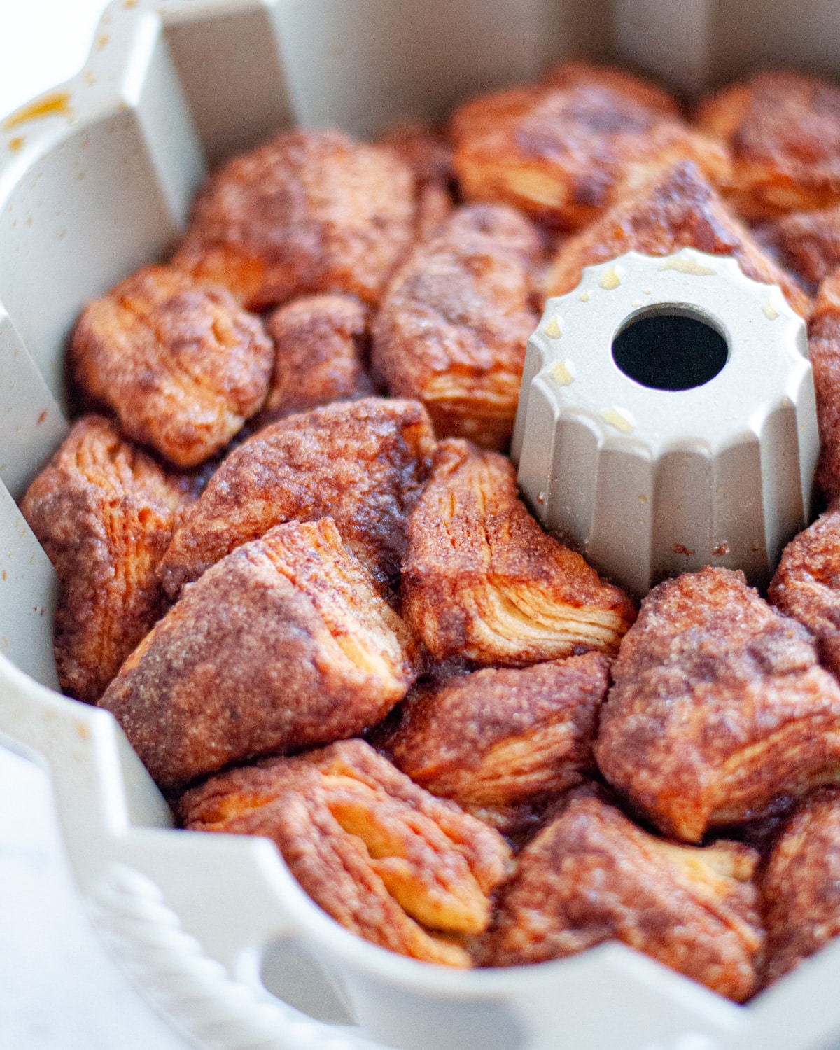 monkey bread fresh out of the oven in a bundt pan. you can see that the biscuits have turned golden brown and the cinnamon-sugar and butter mixture has melted and turned caramely in spots.
