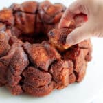 a hand taking a piece of this cinnamon-sugar pull-apart bread out of the monkey bread loaf.