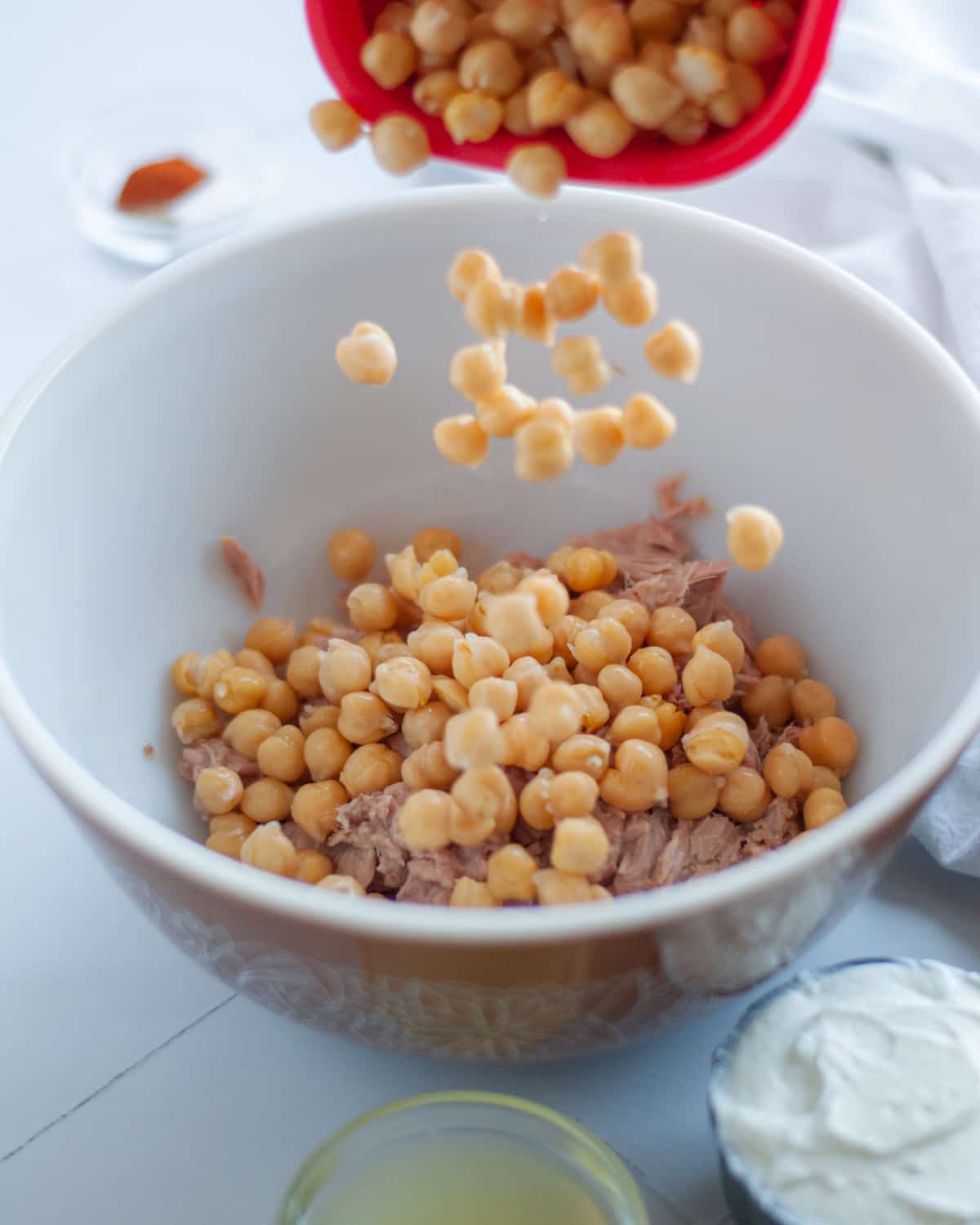 process shot showing how to make Healthy Tuna Salad without Mayo. This shot shows drained and rinsed chickpeas being added to chunk light tuna in a mixing bowl.