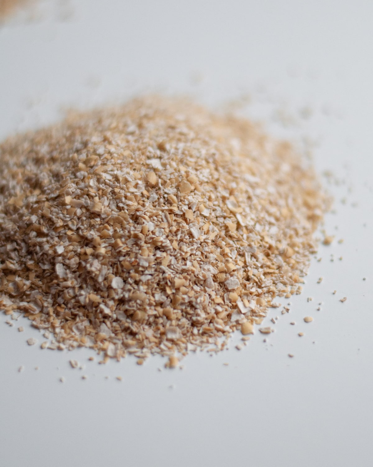 Close up of a pile of oat bran to show the shape and texture of the grain.