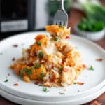 A fork taking a bite from a plate piled high with a hearty scoop of Crockpot Chicken Bacon and Ranch Tater Tot Casserole.