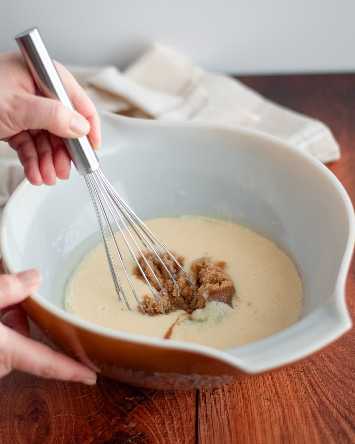 Process shot showing how to make wheat germ muffins; image shows brown sugar being added to the wet ingredients in a large mixing bowl.