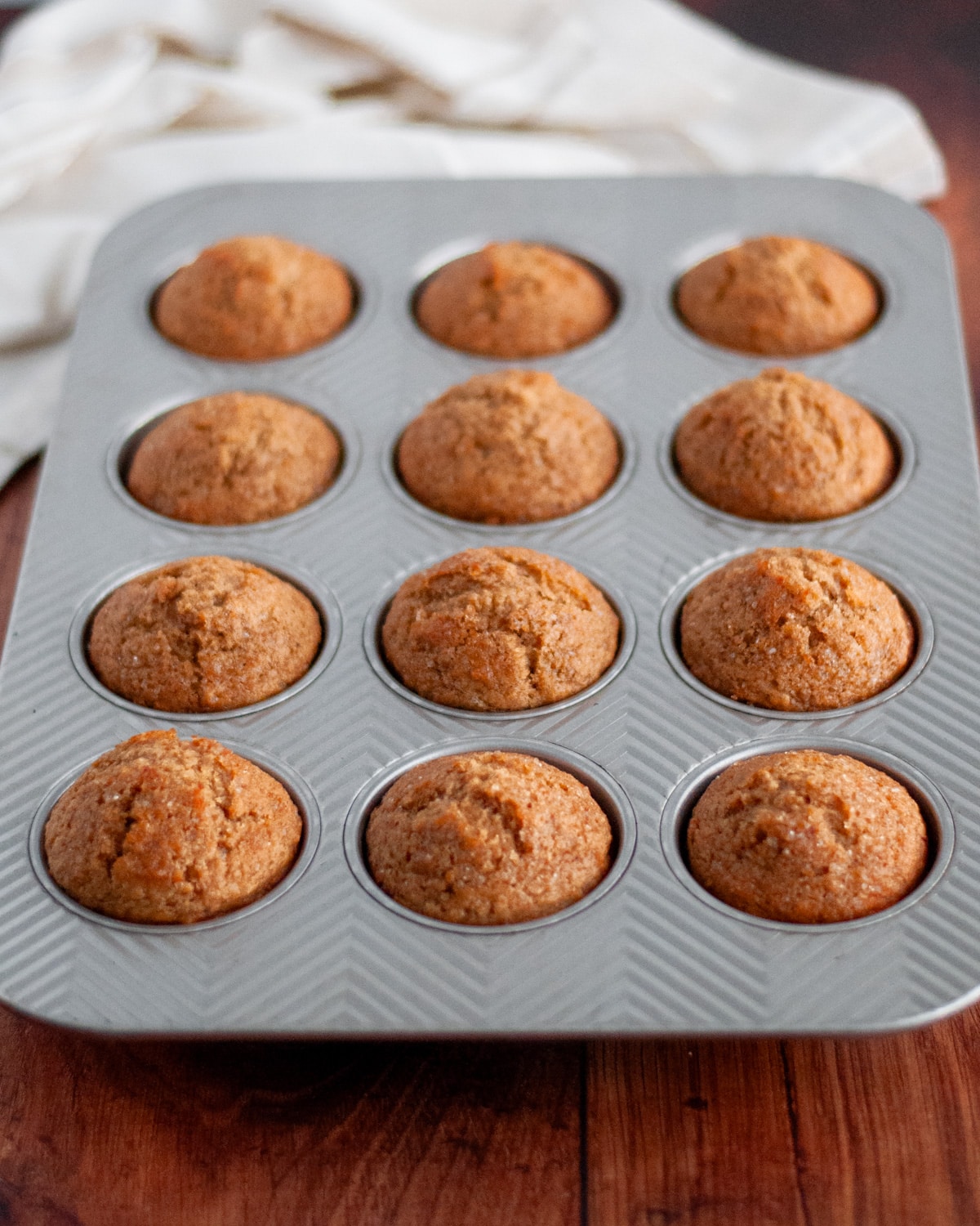Process shot showing how to make wheat germ muffins; image shows perfectly browned and nicely domed muffins fresh out of the oven.
