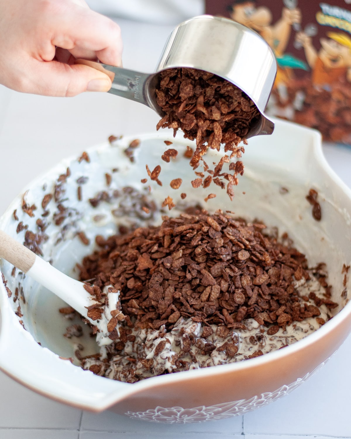 Process shot showing chocolate cereal being added to the melted marshmallows and butter mixture.