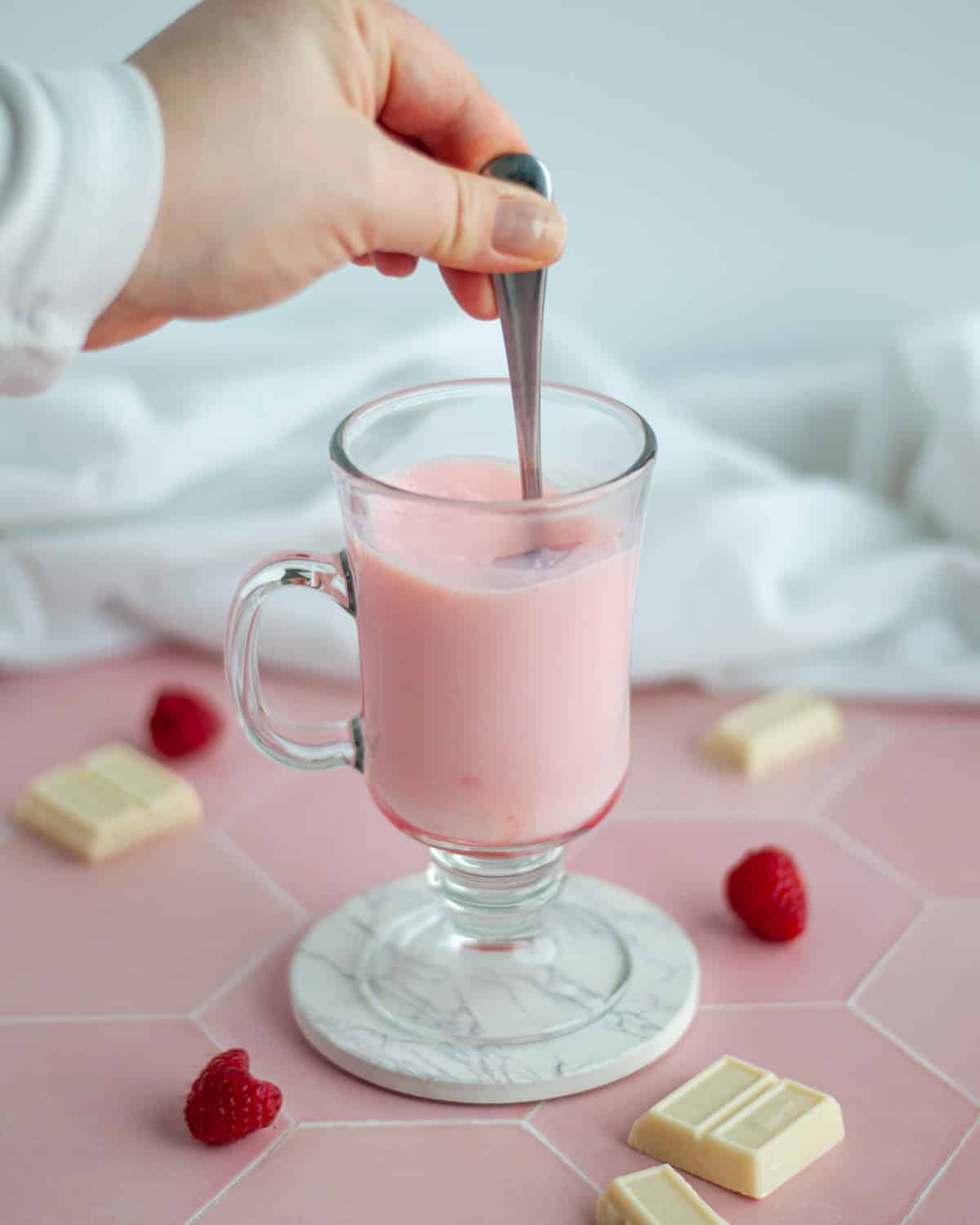 Process shot showing the raspberry syrup, chocolate sauce, and milk being stirred in the mug.