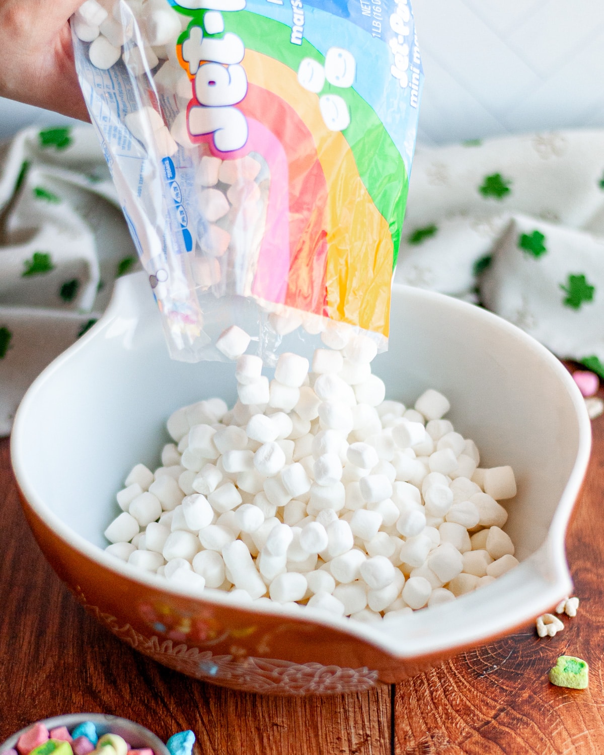 Process shot showing mini marshmallows being added to a large mixing bowl.