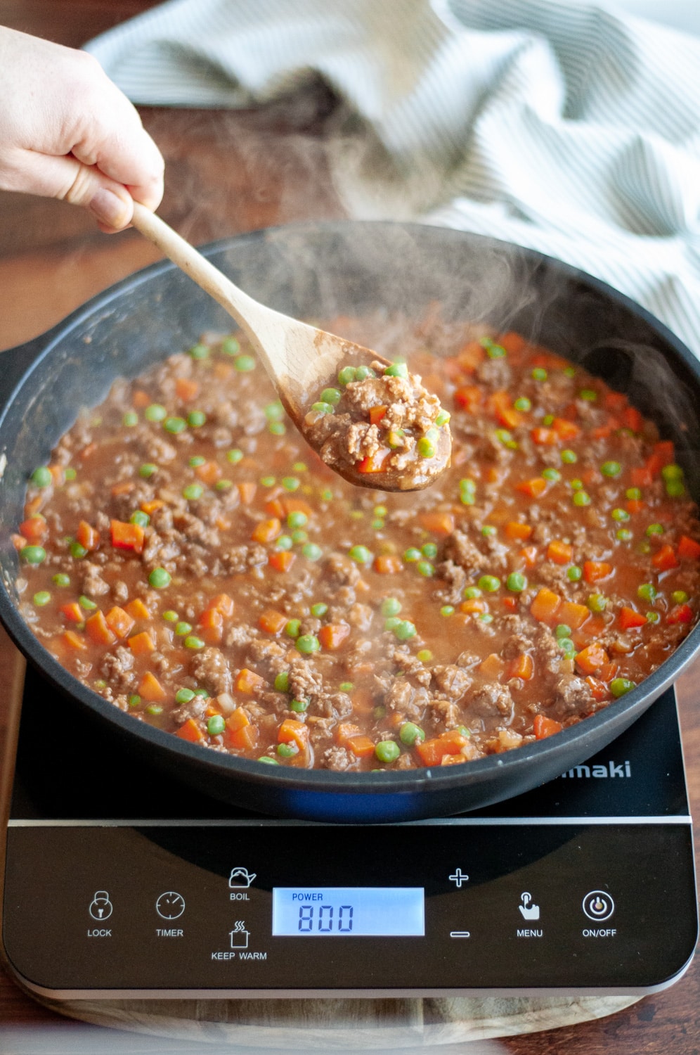 Process shot showing the filling mixture cooked up, with a wooden spoon showing a scoop of the mixture.