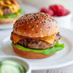 A turkey burger with a slice of cheese and lettuce on a sesame seed bun.