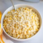 A white serving bowl filled with creamed corn, ready to serve.