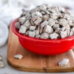 A large red serving bowl filled high with homemade puppy chow.