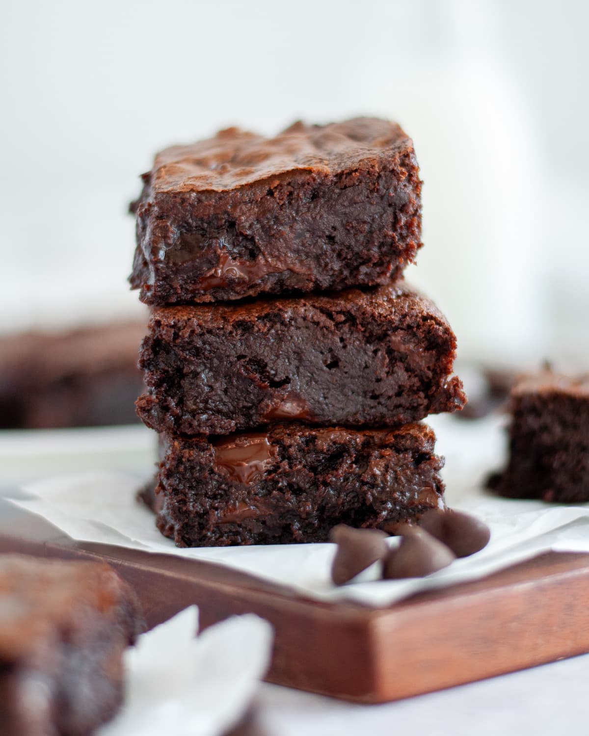 Close up of a stack of brownies sitting on parchment paper and a cutting board.
