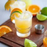 Close up of a skinny margarita in a glass rimmed with salt and garnished with a lime wedge and an orange wedge.