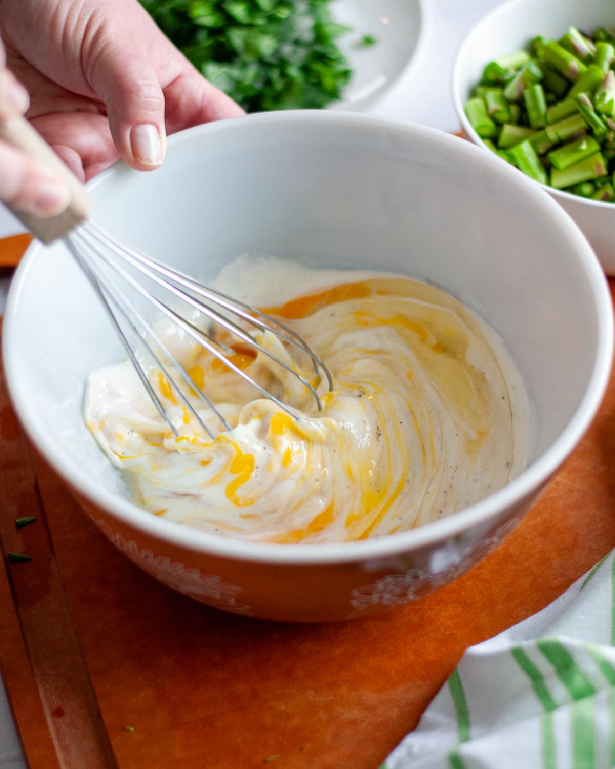 Process shot showing the eggs, cream, and spices being whisked together.