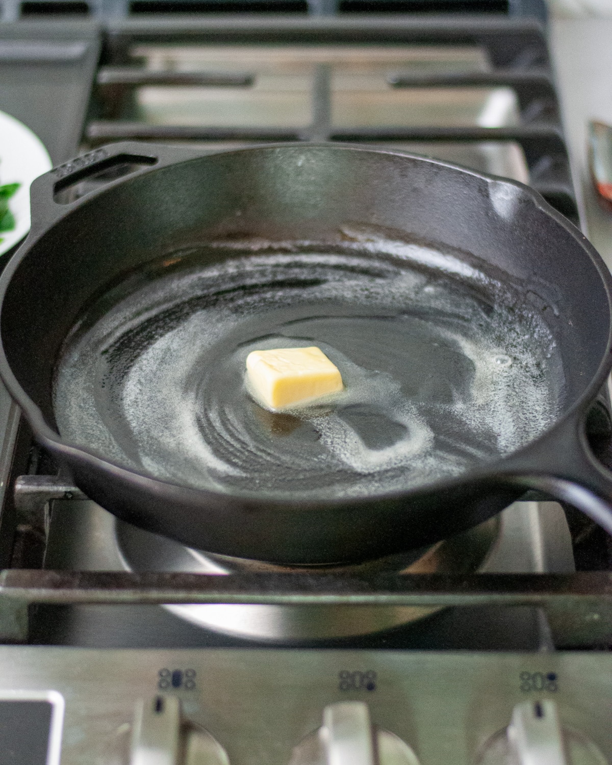 Process shot showing the butter melting in a cast iron skillet.