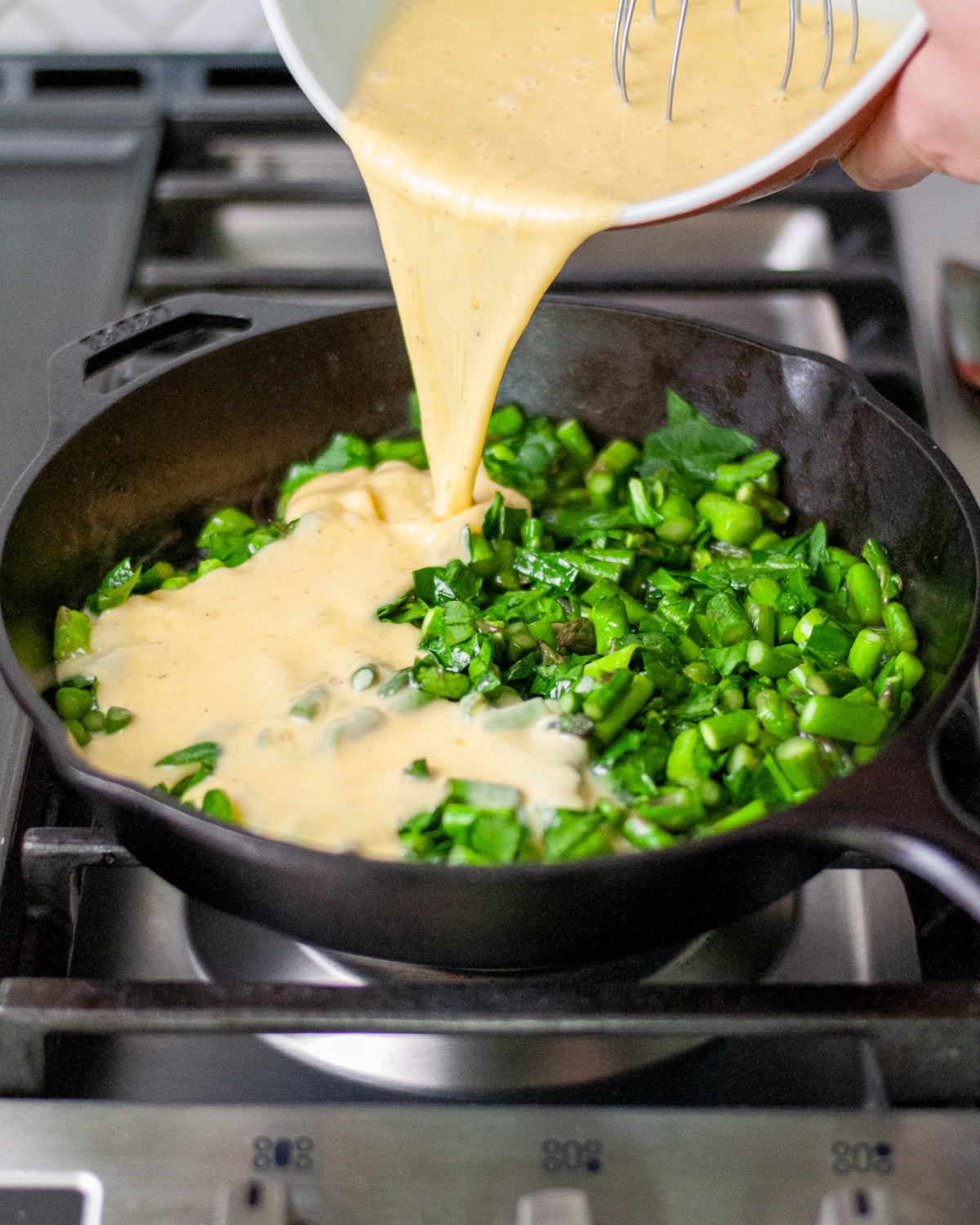 Process shot showing the egg mixture being poured over the vegetables.