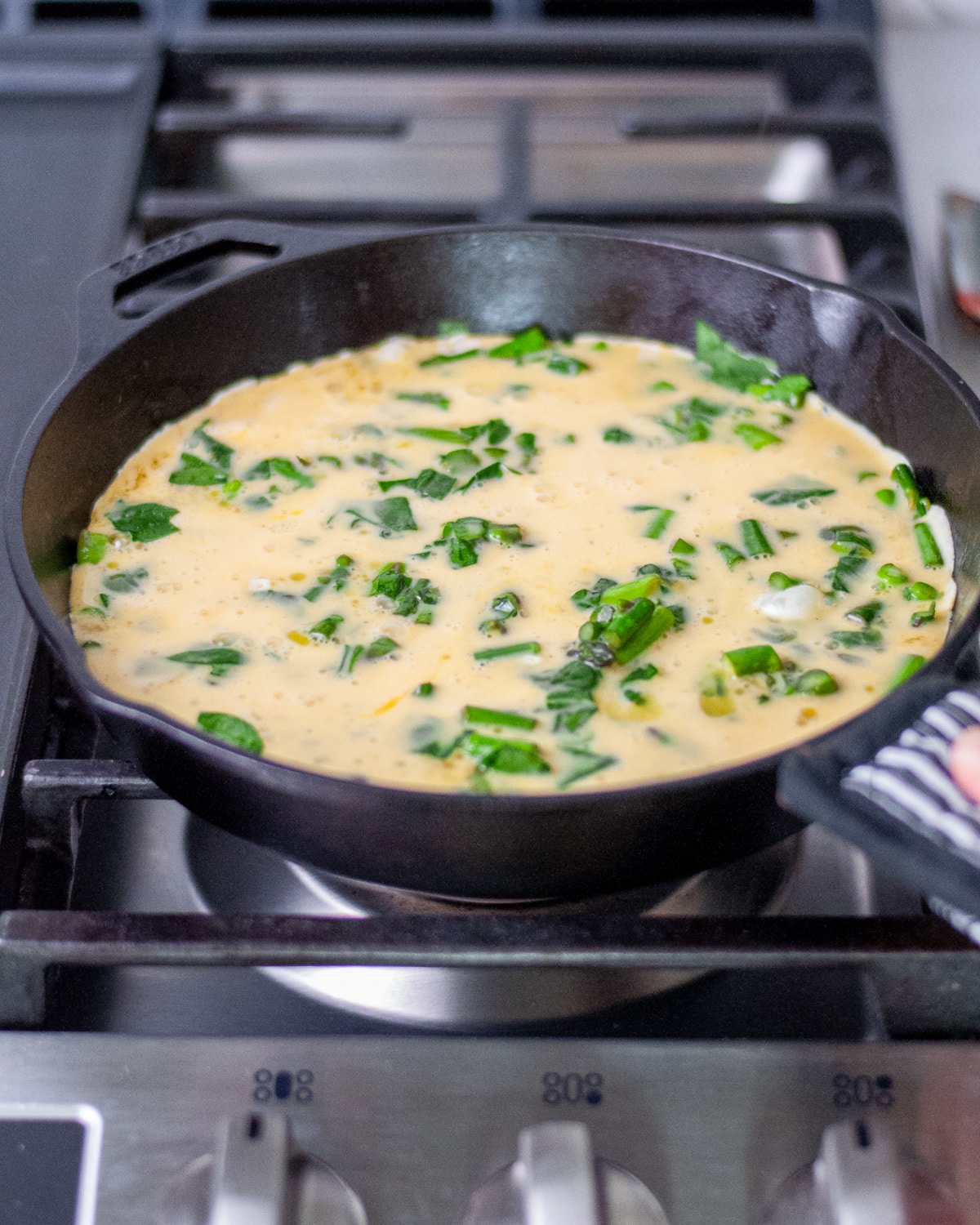 Process shot showing the skillet being lightly shaken to distribute the egg mixture.