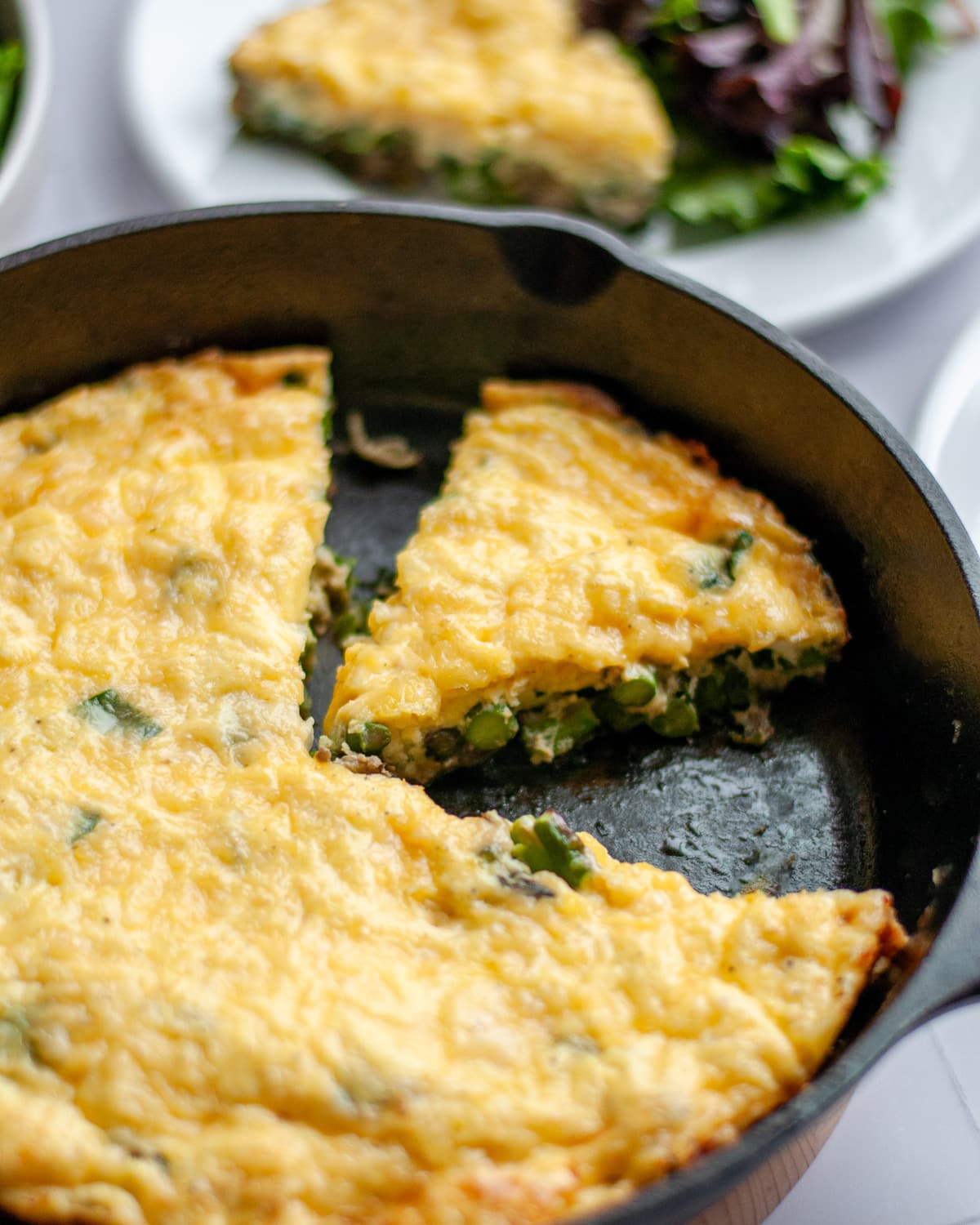 Close up of the frittata, focusing on a slice within the skillet.