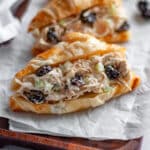 Close up of a shredded chicken salad sandwich, served on a croissant, on a wooden tray.