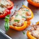 Close up of a stuffed pepper with melted cheese and a sprinkle of fresh basil on top.
