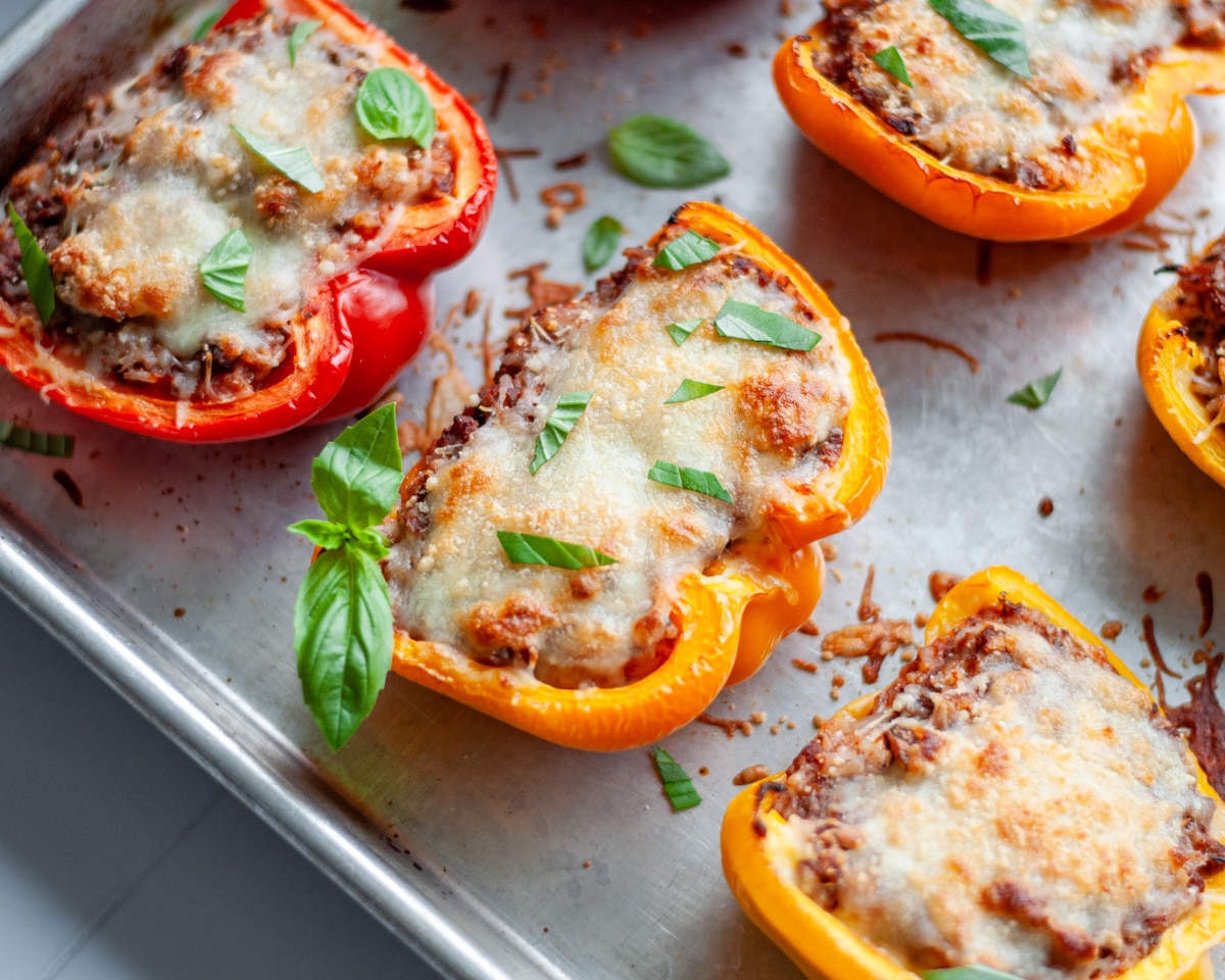 Close up of a stuffed pepper with melted cheese and a sprinkle of fresh basil on top.