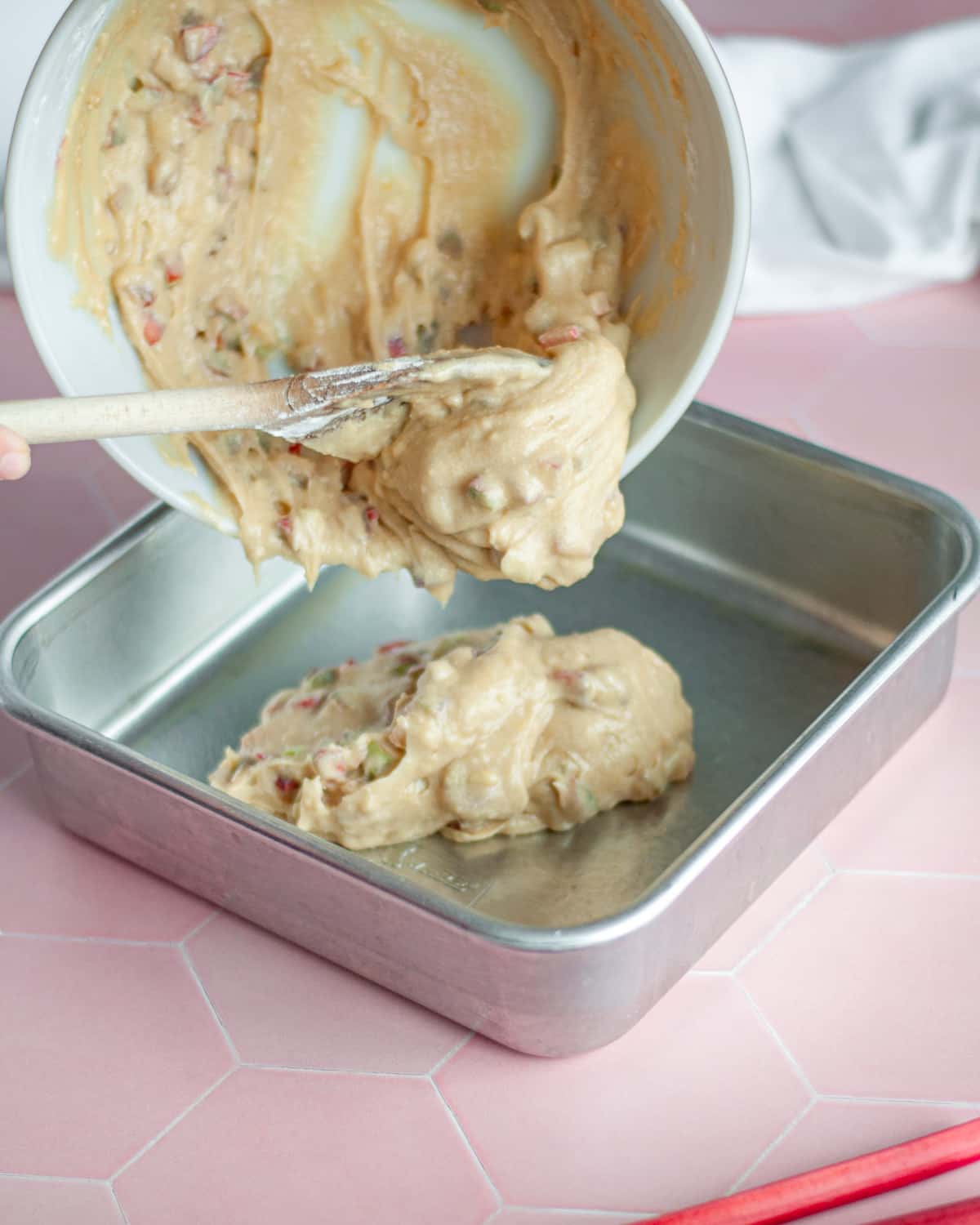 Process shot showing the cake batter being transferred to a greased 9x9 pan.
