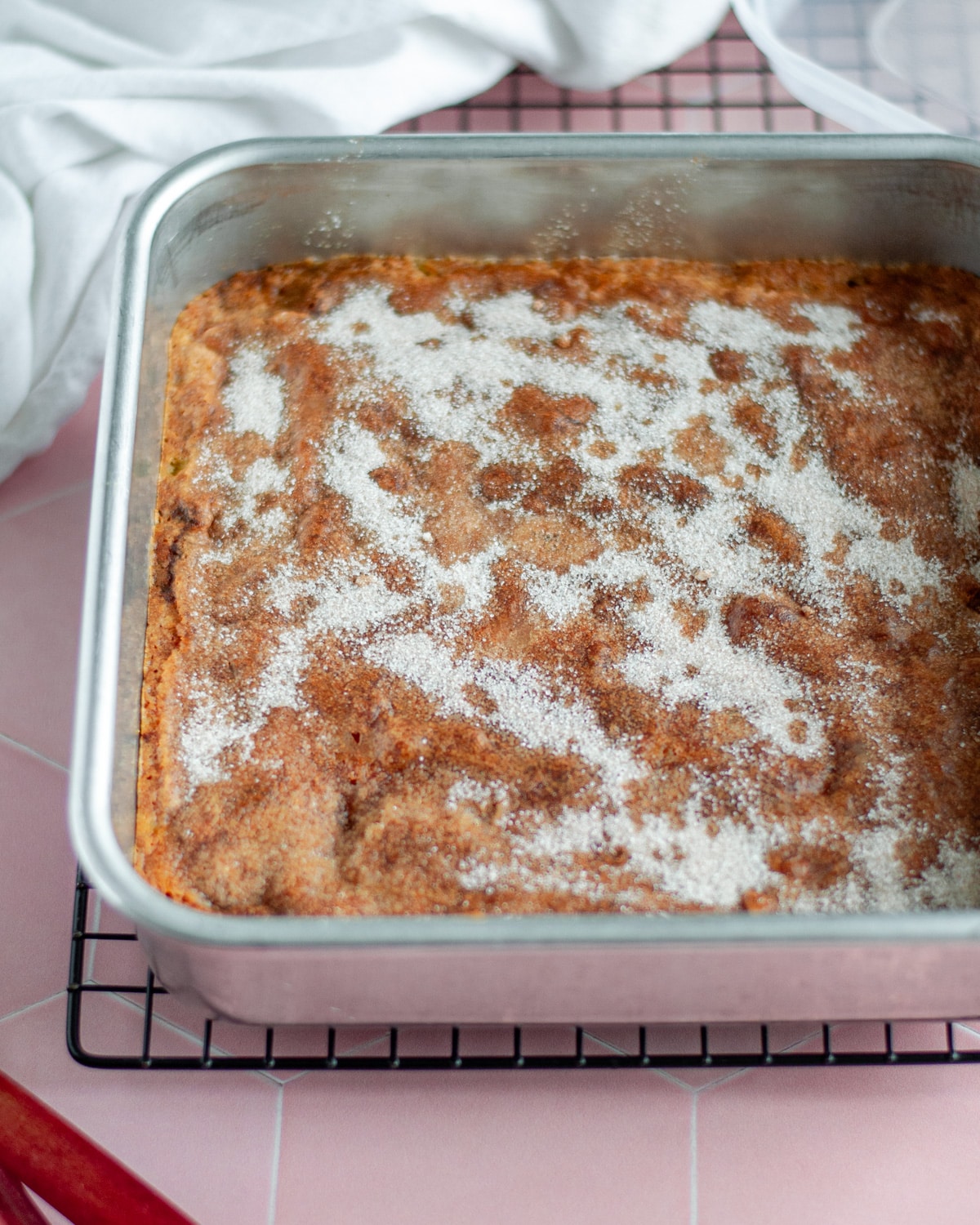 Process shot showing the baked rhubarb cake cooling on a wire rack.