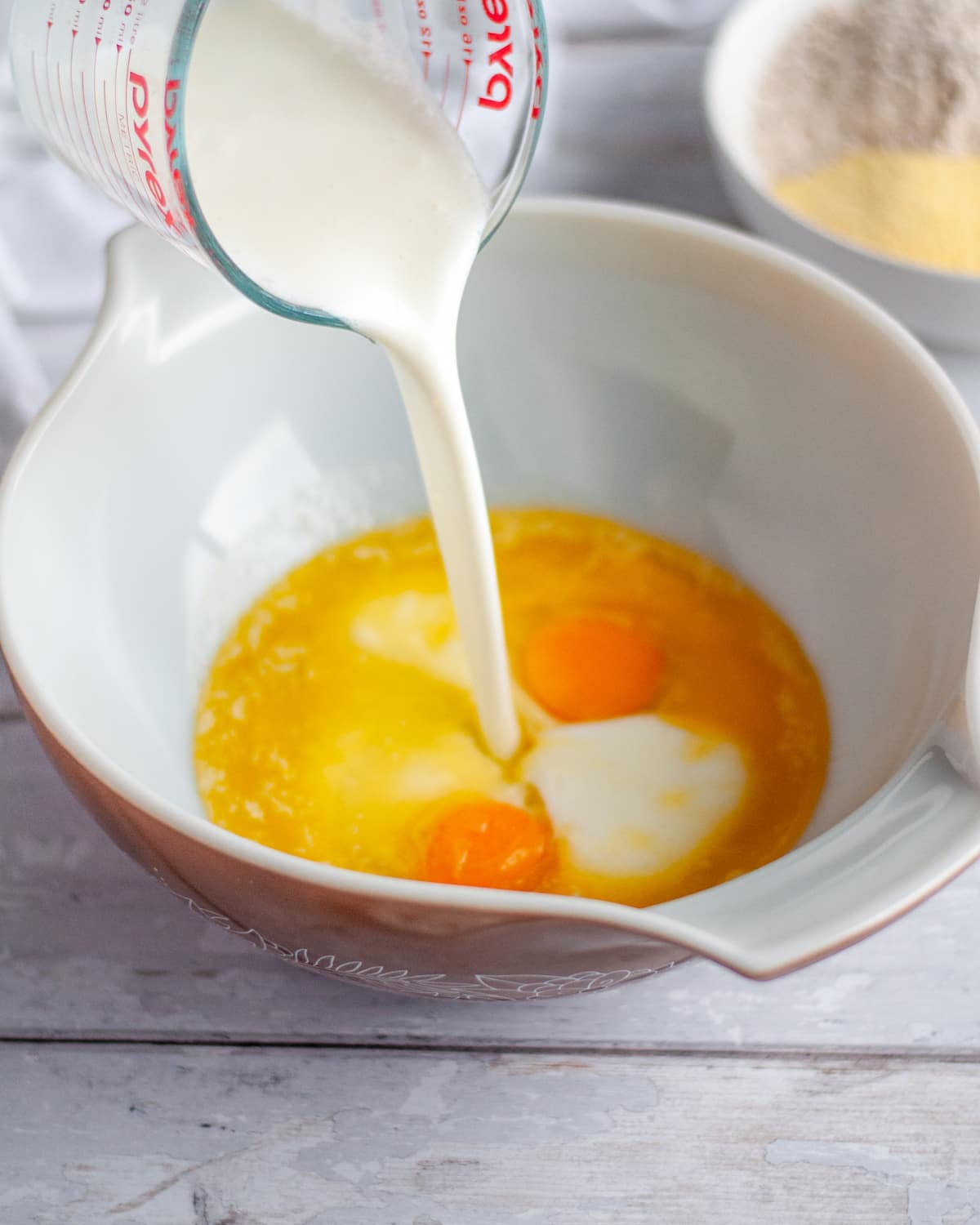 Process shot showing the wet ingredients being added to a large mixing bowl.