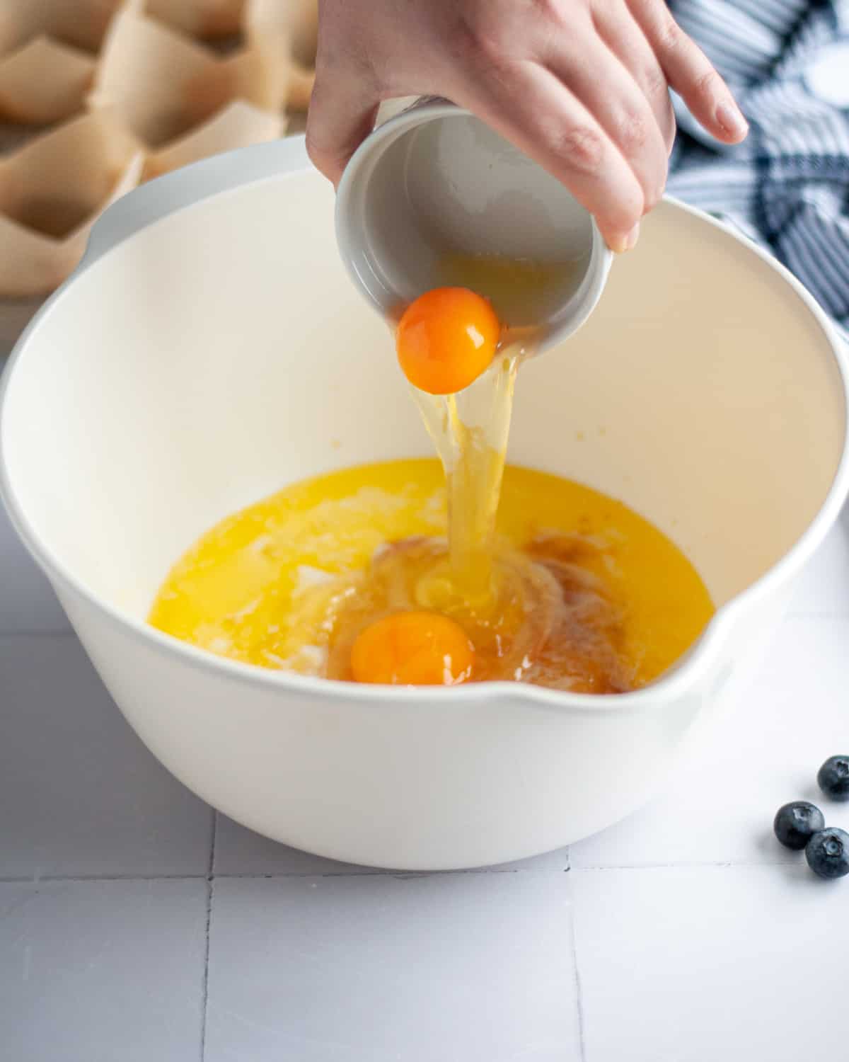 Process shot showing the eggs being added into a large mixing bowl with the other wet ingredients.