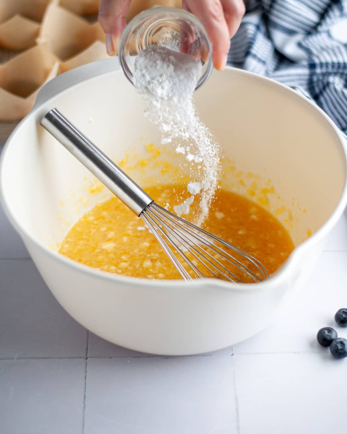 Process shot showing the the salt, baking powder, and baking soda being poured into the wet ingredients.