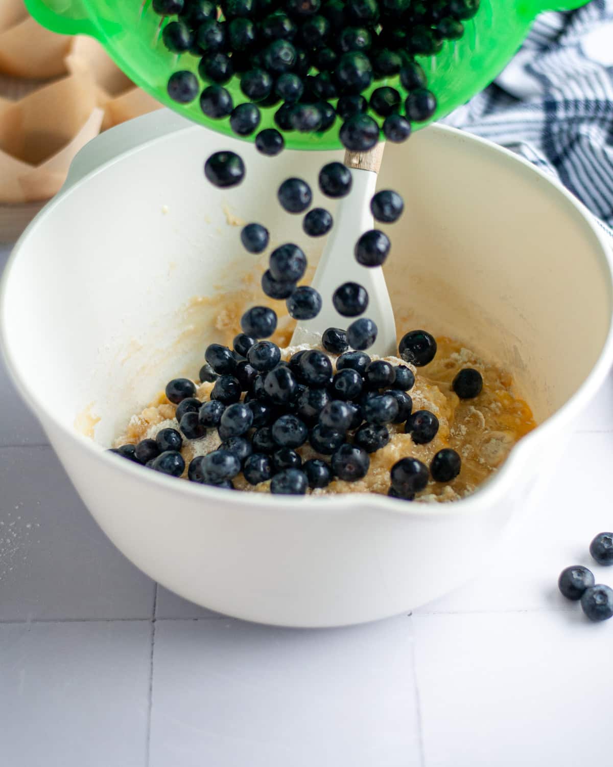 Process shot showing the blueberries being poured into the mixing bowl.