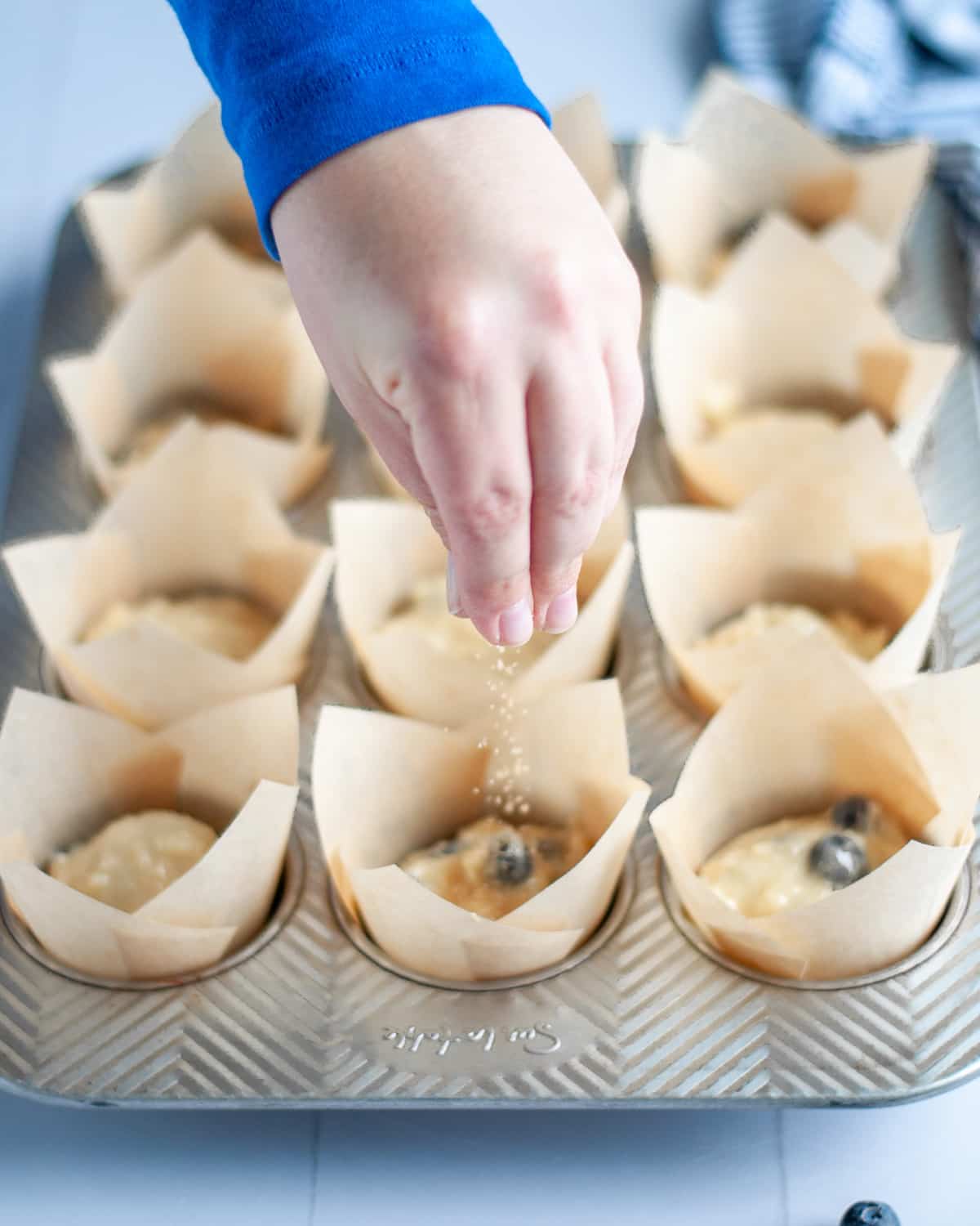 Process shot showing the turbinado sugar being sprinkled onto the batter in the tins.