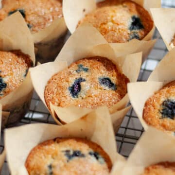 A batch of freshly baked blueberry muffins on a wire cooling rack.