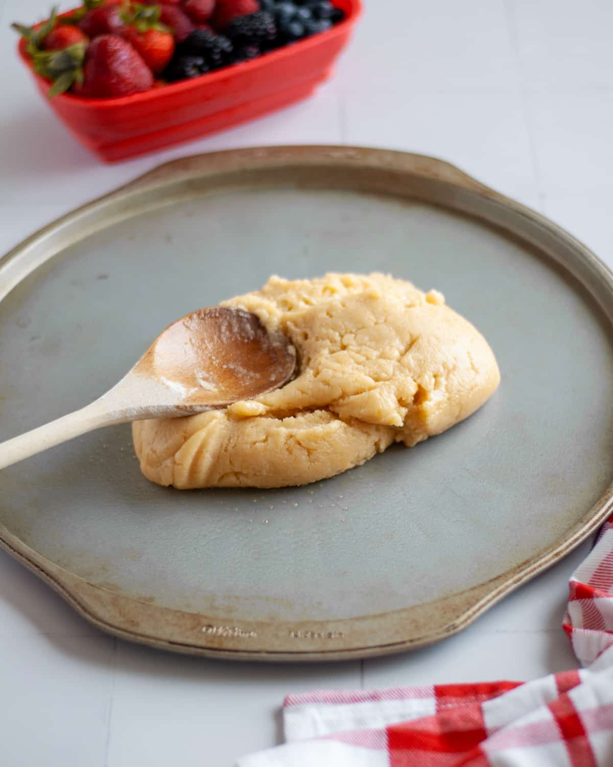 Process shot showing the sugar cookie crust dough transferred to a greased pizza tin.